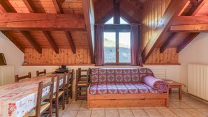 A wooden interior with a loft bed, dining table, chairs, and a window with curtains. - Apartment "Le Ressoutan" with Mountain View and Balcony (Saint-Colomban-des-Villards)