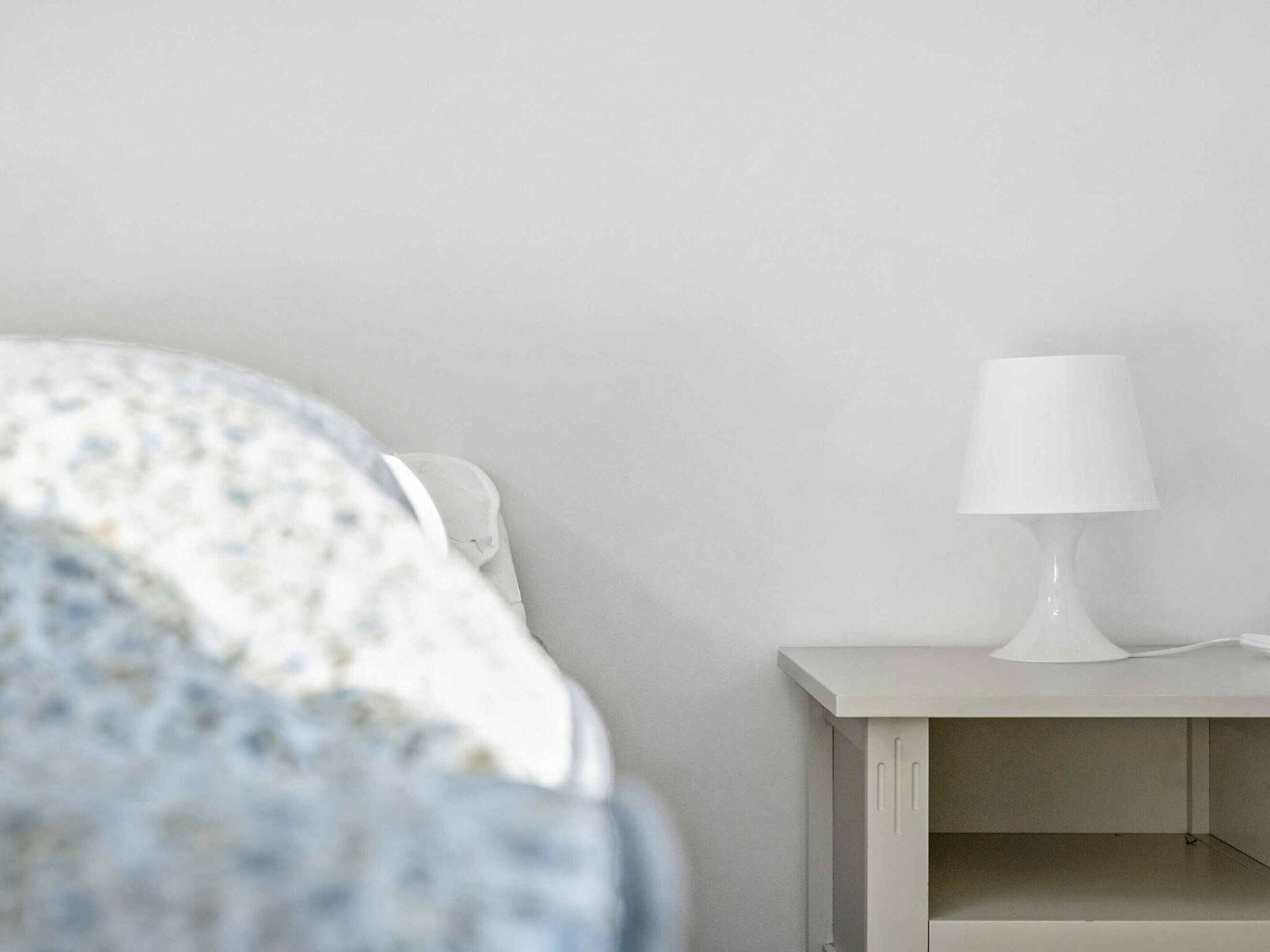 Une chambre à coucher avec un lit, une table de chevet et une lampe.