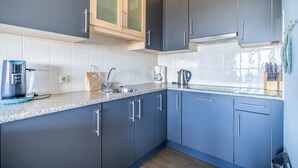 A modern kitchen with blue cabinets, a granite countertop, and stainless steel appliances.