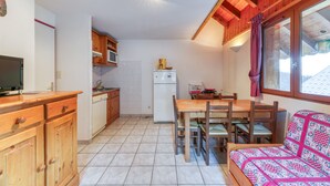 Une cuisine compacte avec des meubles en bois, un réfrigérateur et un coin repas comprenant une table et des chaises.