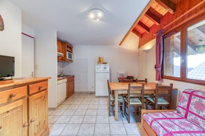 Une cuisine compacte avec des meubles en bois, un réfrigérateur et un coin repas comprenant une table et des chaises.