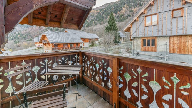 Un balcon en bois avec un banc, une vue sur une montagne et un bâtiment doté d’un toit en pente.