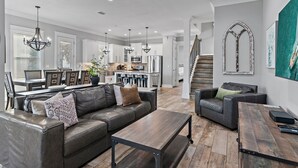 Ein modernes Wohnzimmer mit einer Ledersofa, einem Holztisch und einem Essbereich im Hintergrund.