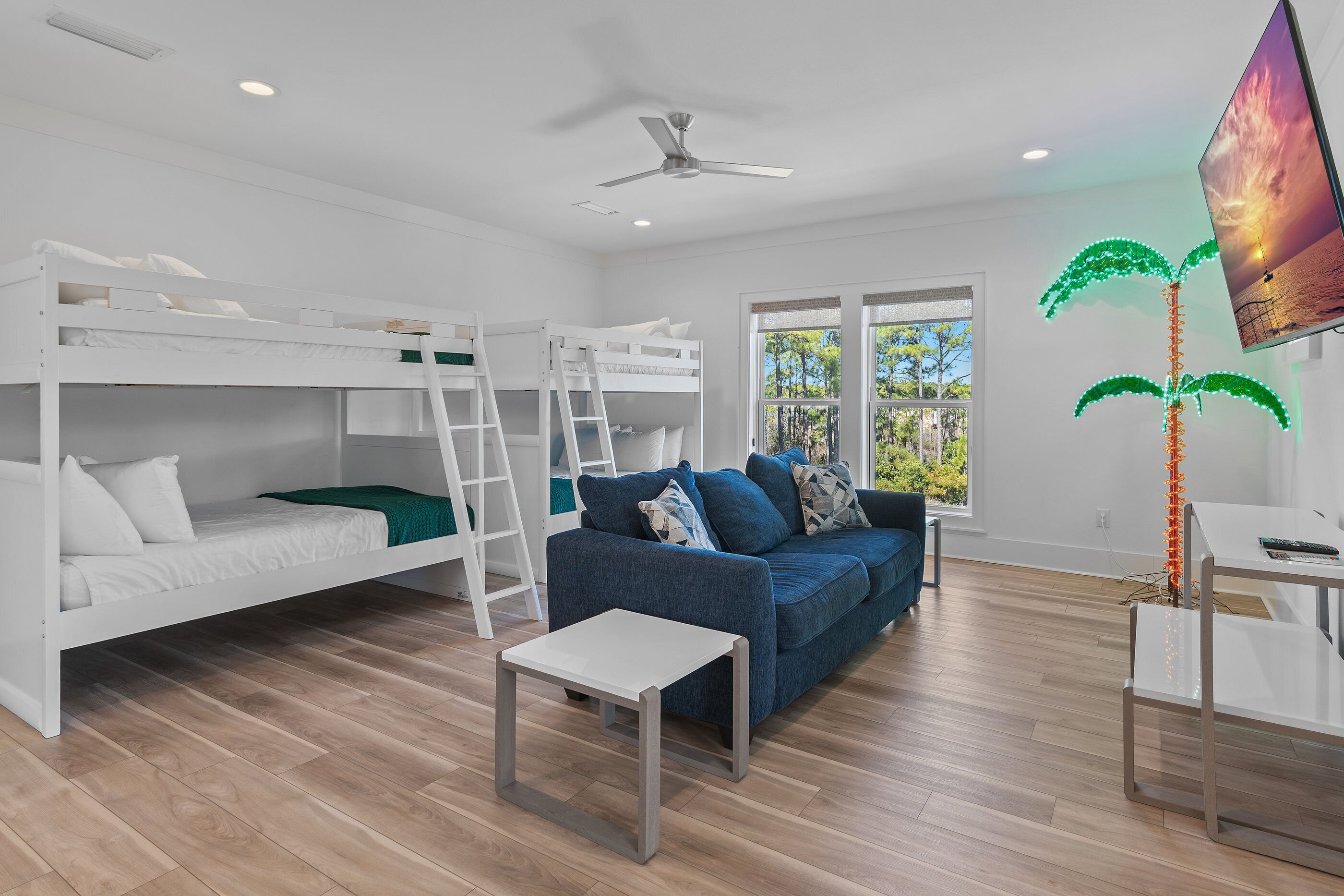 A modern room with a bunk bed, a sofa, a small table, and a ceiling fan.