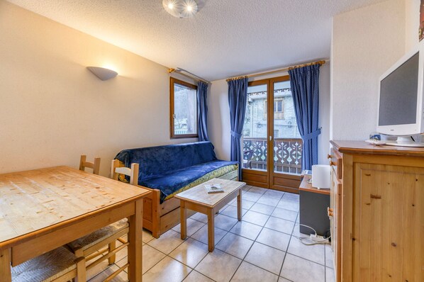 A small room with a wooden table, a sofa, a small table, a cabinet, and a television.