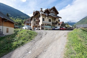 Un bâtiment à deux étages, avec un magasin de ski au rez-de-chaussée, une vue sur la montagne et une allée de gravier menant à l’entrée.