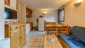 Un espace de vie compact comprenant un coin cuisine, un coin repas et un espace détente avec un canapé et une table.