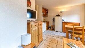 Une cuisine compacte dotée de meubles en bois, d’un four à micro-ondes encastré, d’un réfrigérateur et d’un coin repas avec une table et des chaises.