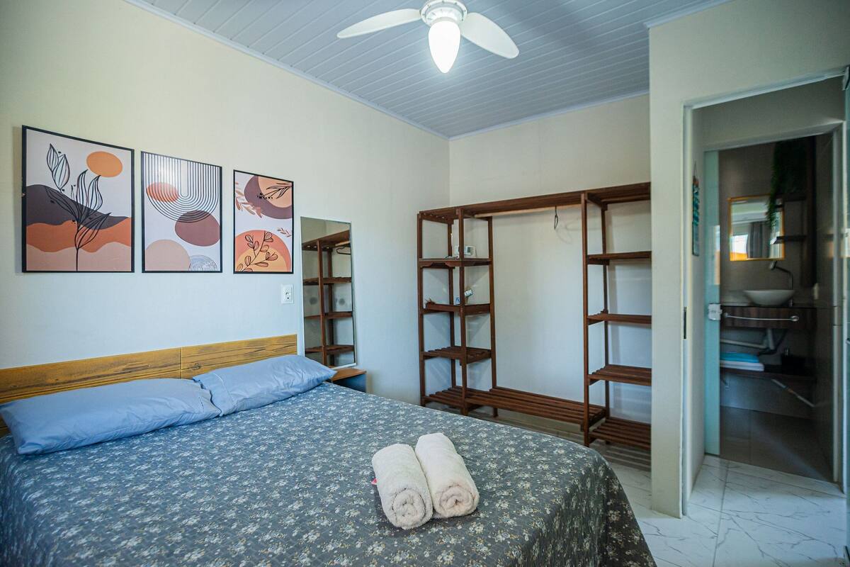 A bedroom with a bed, a wardrobe, and a bathroom visible through an open door.