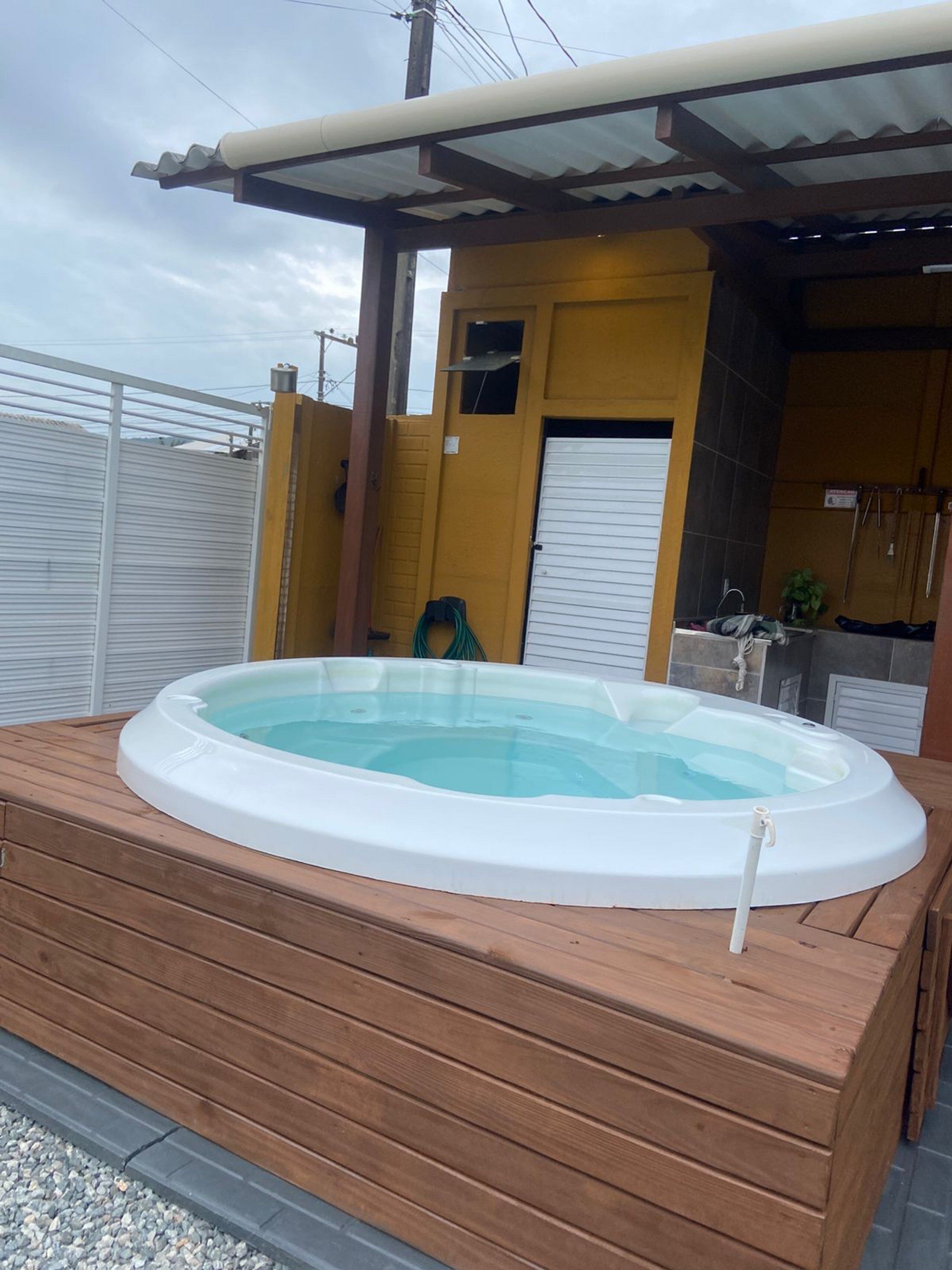 A hot tub on a wooden deck with a covered patio area.