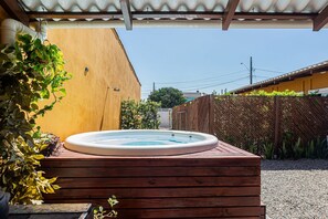 Ein Whirlpool auf einer Holzterrasse mit einer gelben Wand und einem Holzzaun im Hintergrund.