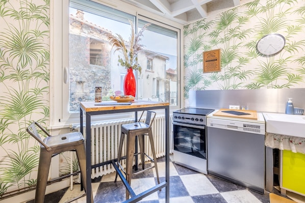 A kitchen with a window, a red vase, a clock, and a radiator.