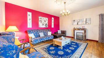 A living room with a red wall, blue patterned sofa, a wooden coffee table, and a fireplace.