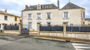 Un immeuble à deux étages doté d’une entrée fermée par un portail, d’une allée et d’un passage piéton.