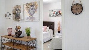 A room with a bed, a bedside table with a vase and a sculpture, and a wall with three paintings. - Holiday Home 'Casita Perla' with Private Pool, Wi-Fi and Air Conditioning (Conil de la Frontera)