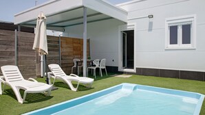 A modern outdoor pool area with a covered seating area and a wooden wall. - Holiday Home 'Casita Perla' with Private Pool, Wi-Fi and Air Conditioning (Conil de la Frontera)