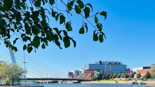 A marina with boats docked along a cobblestone waterfront, a bridge in the background, and modern buildings across the water. - Spacious City Retreat with Private Sauna (Helsinki)