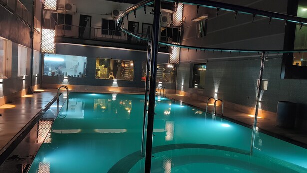 An indoor swimming pool with a glass barrier, a metal ladder, and a tiled floor. - Ananya Hotel  (Digha)
