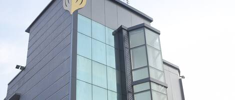A modern building with a glass facade and a logo on the top.