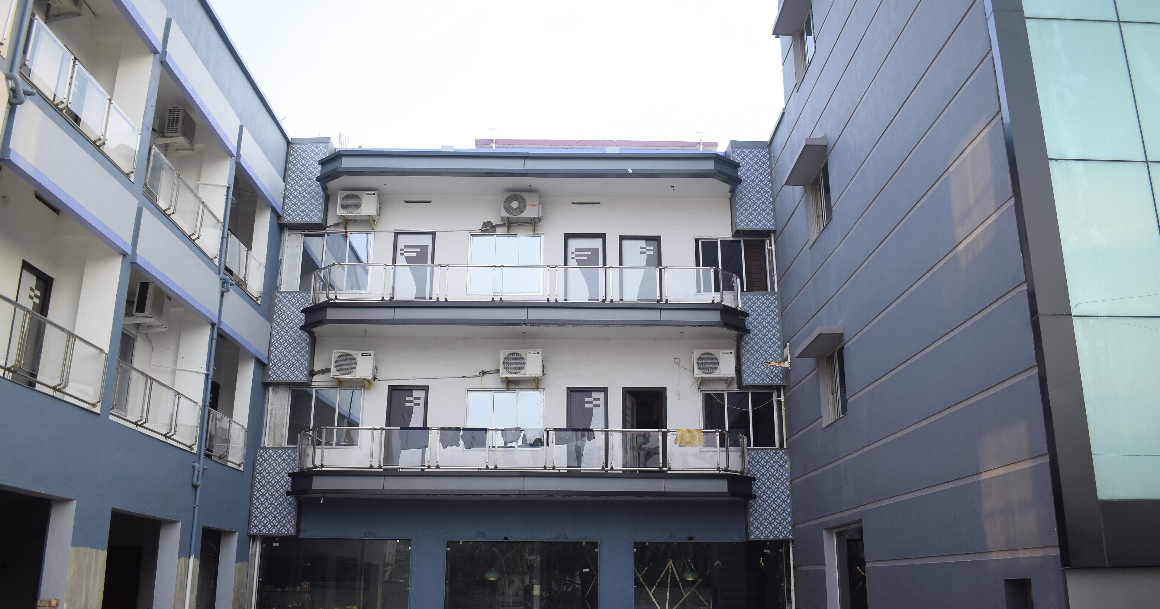Un edificio de varios pisos con balcones, unidades de aire acondicionado y fachada decorativa.