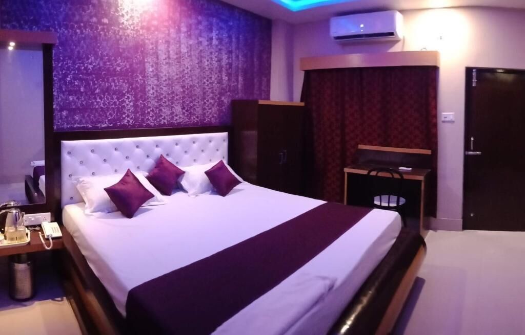 Camera d'albergo con un letto grande, un comodino con telefono e lampada, un armadio e un condizionatore d'aria.