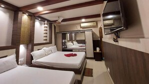 A hotel room with two beds, a TV, a mirror, and a wardrobe. - Ananya Hotel  (Digha)