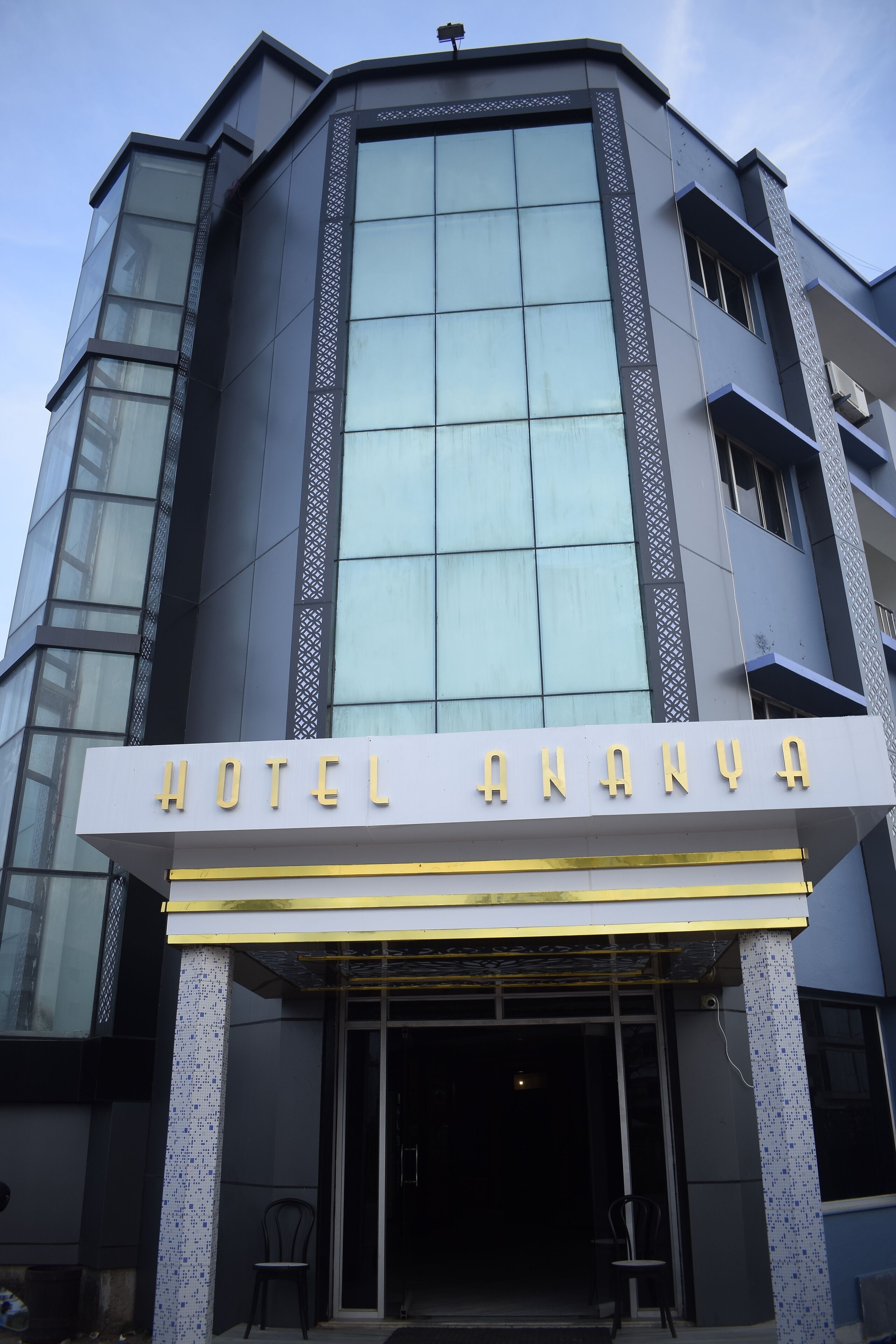 A hotel with a modern facade, large glass windows, and a sign reading "HOTEL ANANYA".