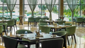 A spacious indoor dining area with tables and chairs arranged for guests. - Golden Sands - By The Bay Resorts (Bapatla)