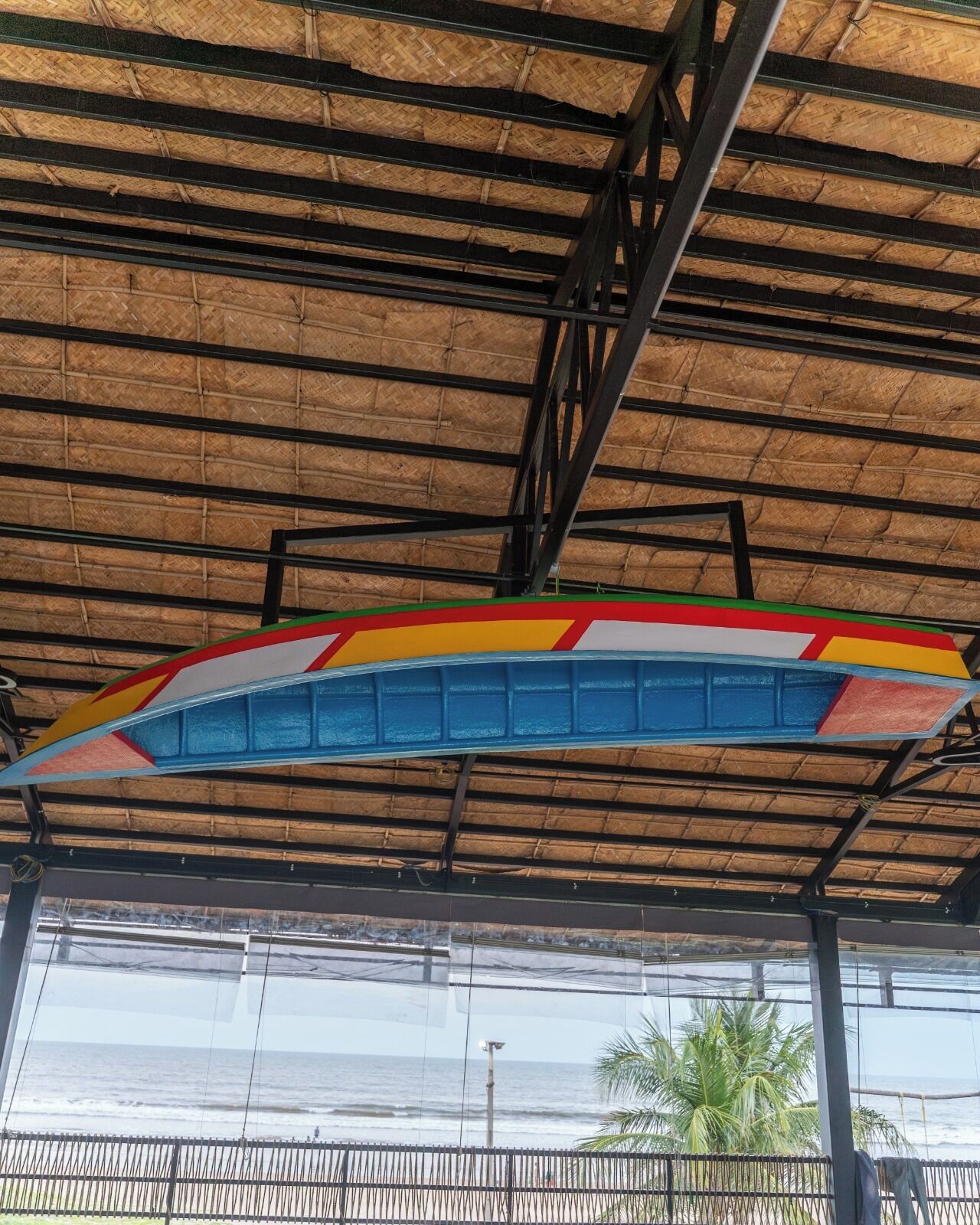 A beachside view with a thatched roof structure and a colorful boat decoration.