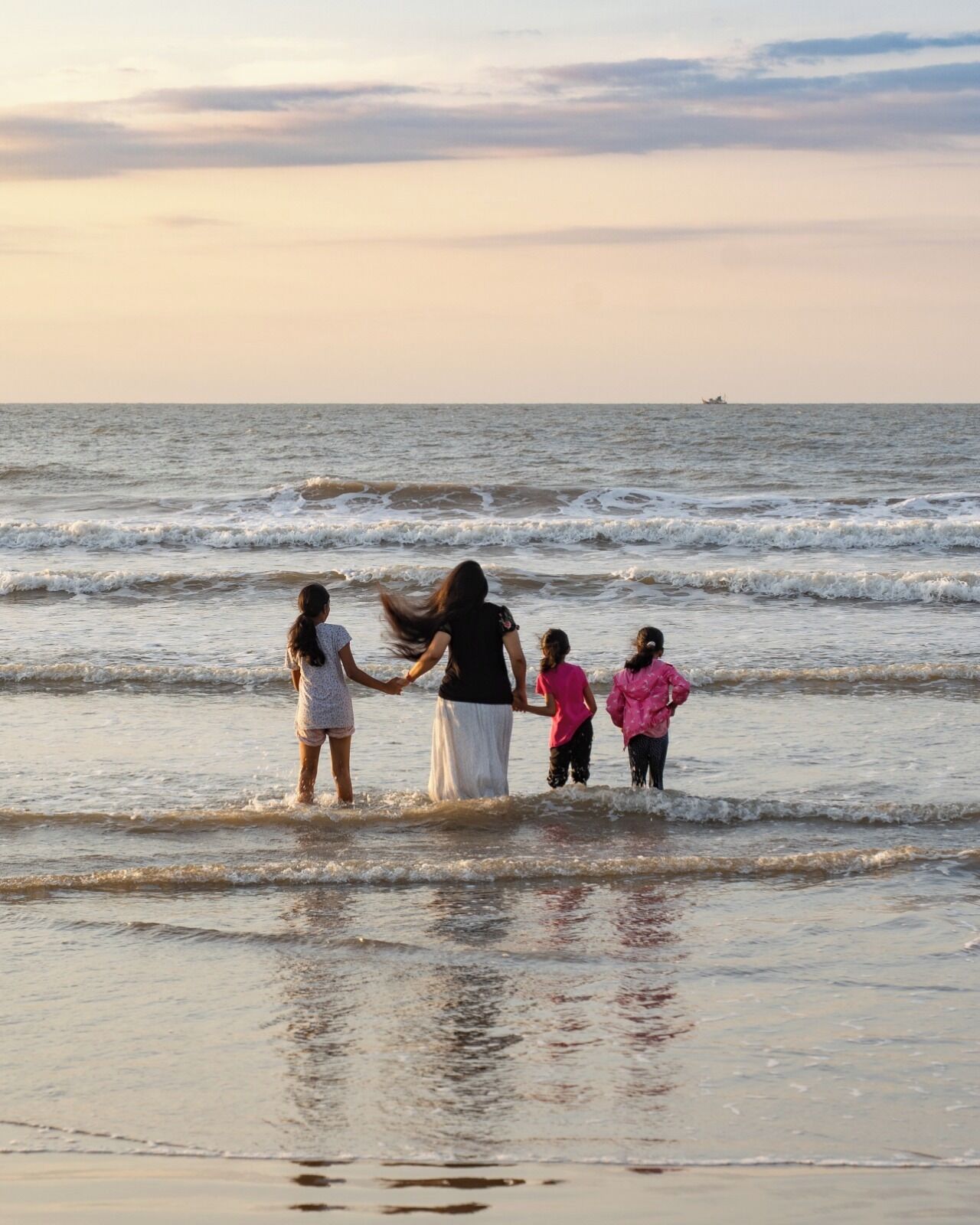 A family walking along a beach with waves.