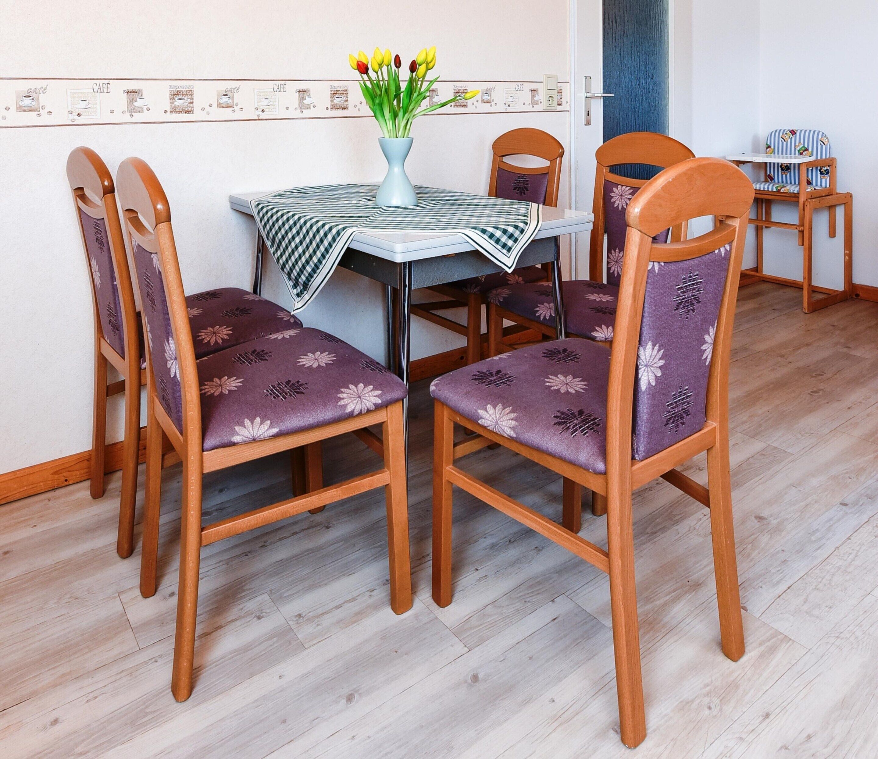 A dining area with a table, chairs, and a vase with flowers.