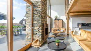 Amplia sala de estar con chimenea de piedra, asientos cómodos y un gran ventanal con vistas al exterior.