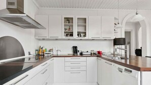 A modern kitchen with white cabinetry, a wooden countertop, and a built-in dishwasher.
