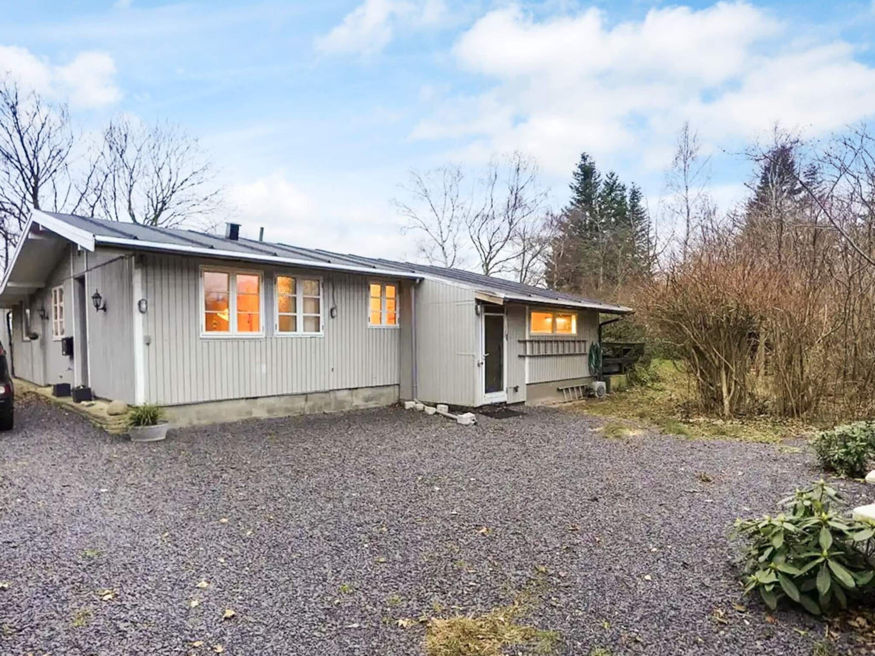 Een twee verdiepingen tellend huis met een grindpad en een klein portaaltje.