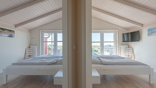 Een kamer met een spiegel, een bed, een televisie en uitzicht op het exterieur.