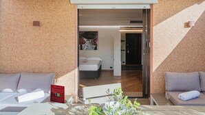 A hotel room with a bed, a small table, a sofa, and a glass table with plants. - Beachfront Studio with Terrace by Wonderful Italy (Genoa)