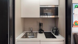 A compact kitchenette with a stainless steel sink, a black induction cooktop, a microwave, and a coffee machine. - Beachfront Studio with Terrace by Wonderful Italy (Genoa)
