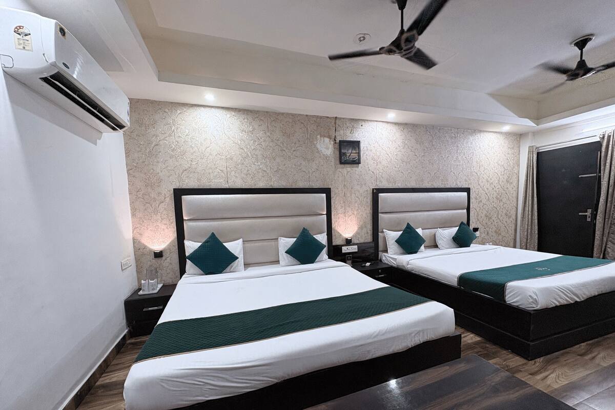 Une chambre d’hôtel avec deux lits, un ventilateur de plafond, un appareil de climatisation et un plancher en bois.