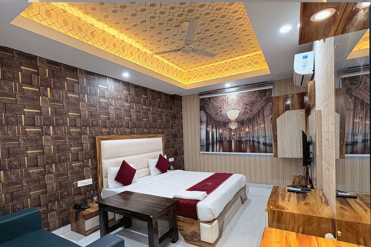 Une chambre d’hôtel avec un grand lit, un bureau, une chaise, un luminaire au plafond et un téléviseur fixé au mur.