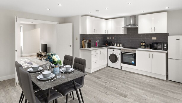 A modern kitchen with white cabinets, a built-in oven, and a microwave. - Spacious 2-floor Flat Near Weymouth Seafront (Weymouth)