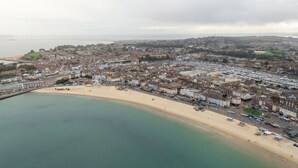 An aerial view of a coastal town with a sandy beach, a large Ferris wheel, and a marina filled with boats. - Spacious 2-floor Flat Near Weymouth Seafront (Weymouth)