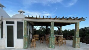 A covered outdoor seating area with wooden stools and a pergola structure.