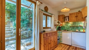 A kitchen with wooden cabinets, a white dishwasher, and a green tiled backsplash. - Gite du bas – in La Rouquette, a charming little hamlet (Saint-Privat)