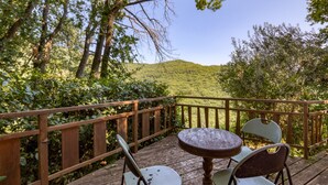 A wooden deck with a table and chairs overlooking a hilly landscape. - Gite du bas – in La Rouquette, a charming little hamlet (Saint-Privat)