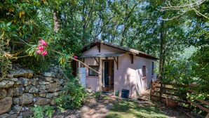 A rustic cabin with a stone wall, a wooden fence, and a garden path leading to the entrance. - Gite du bas – in La Rouquette, a charming little hamlet (Saint-Privat)