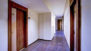 A hallway with wooden doors, a tiled floor, and a sign indicating room number 210.