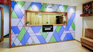 A reception area with a geometric patterned wall, a reception desk, and a sign indicating 'Company Serviced'.