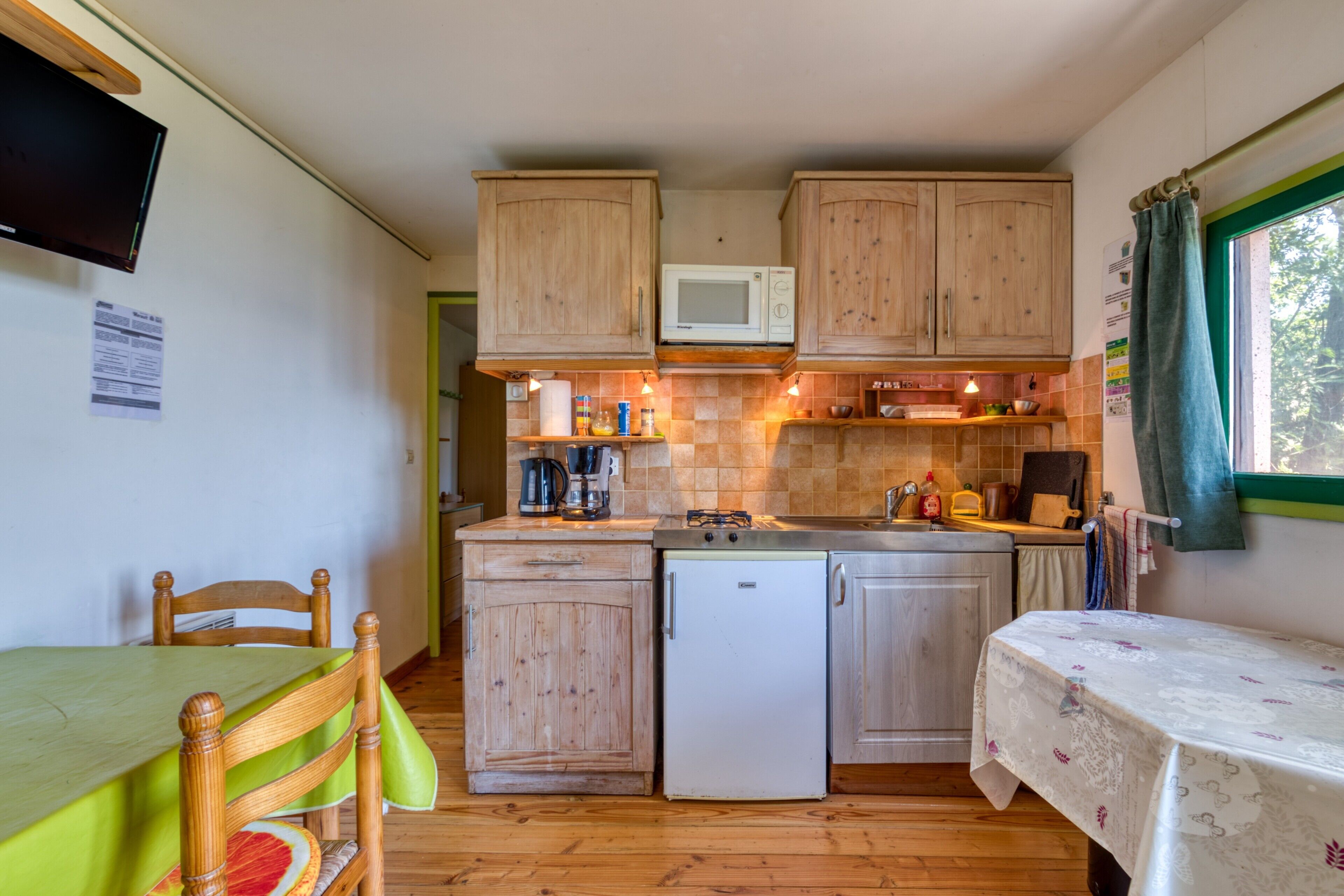 Una cocina compacta con armarios de madera, un microondas, un refrigerador y un comedor con mesa y sillas.