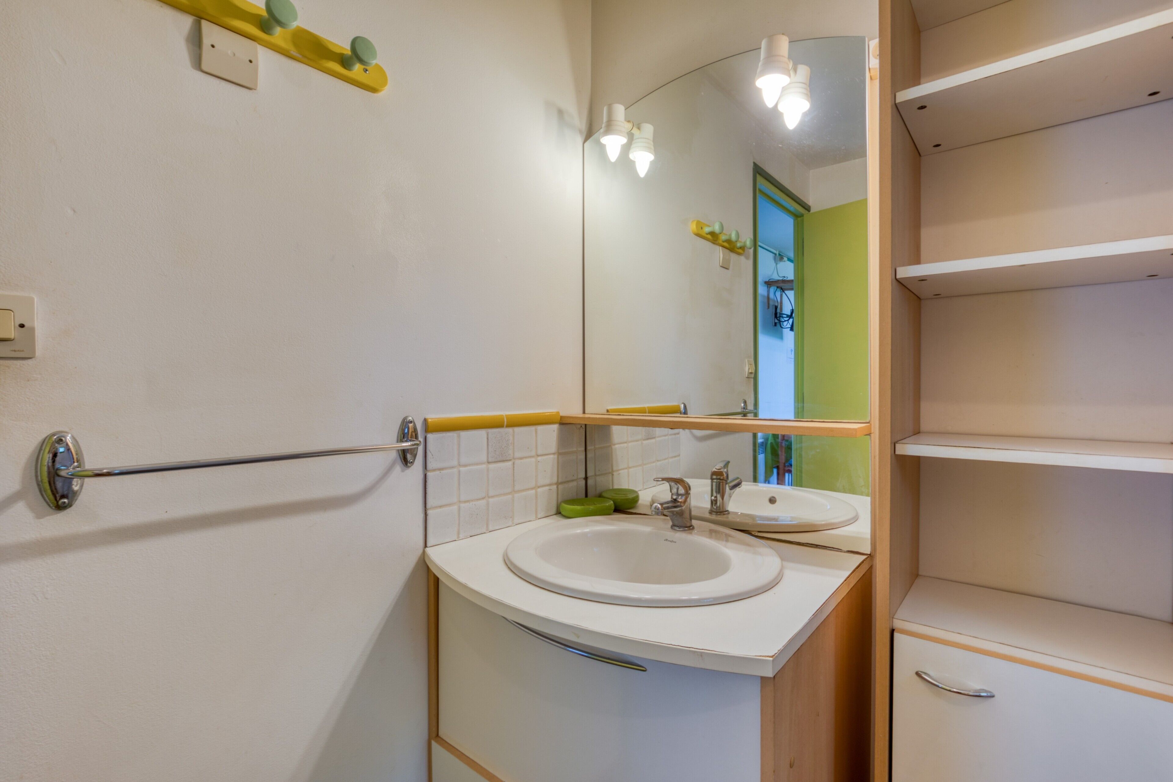 A bathroom with a sink, mirror, and towel rack.
