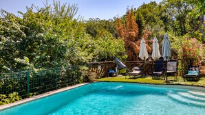 A swimming pool surrounded by greenery, with lounge chairs and umbrellas. - Gite du haut – in La Rouquette, a charming little hamlet (Saint-Privat)